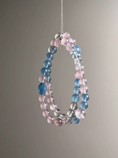 Wrapped composition—pastel aquamarine and rose quartz rhythm with bright clear-quartz highlights; slim, airy silhouette.