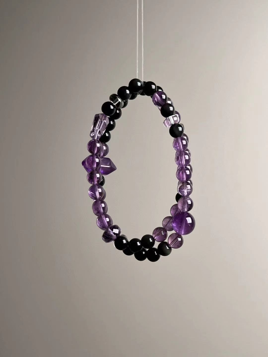 Full-length loop showing the double-wrap strand layout with even spacing of obsidian and clear quartz
