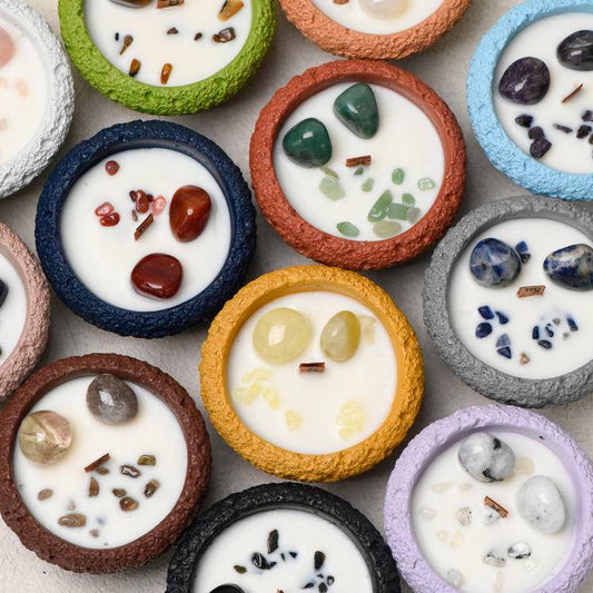 Group hero of Zodiac Intention Candles in textured color vessels with gemstones set in creamy wax and wood wicks.