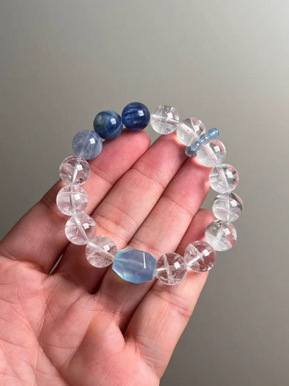 Hand shot of the Ocean Sanctuary bracelet—white phantom quartz, kyanite and aquamarine runner beads, ~12 mm rounds with ice-clear clarity.