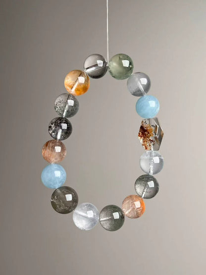 Mixed gemstone bracelet featuring golden rutile, citrine, gray moonstone, copper rutile and clear quartz, tapered 14–11 mm.