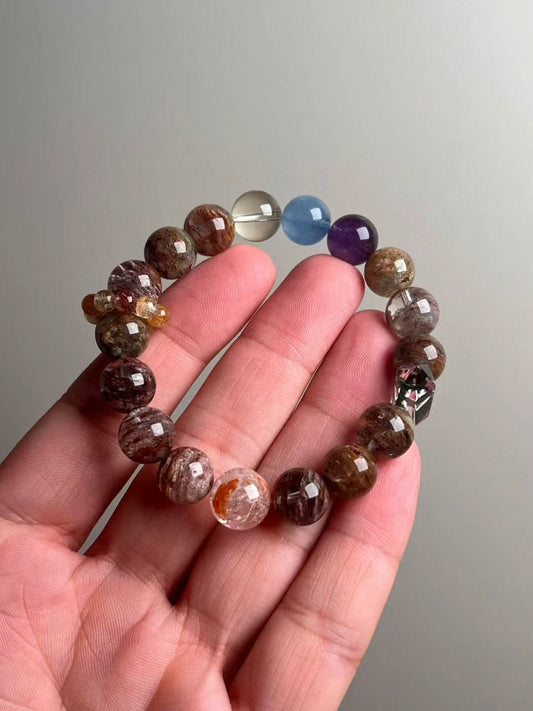 Hand holding Seven-Spectrum Phantom Quartz multigem bracelet, 11–11.5 mm beads