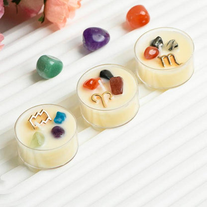 Lifestyle scene of Aries gemstone tea-light with surrounding tumbled stones on white surface.