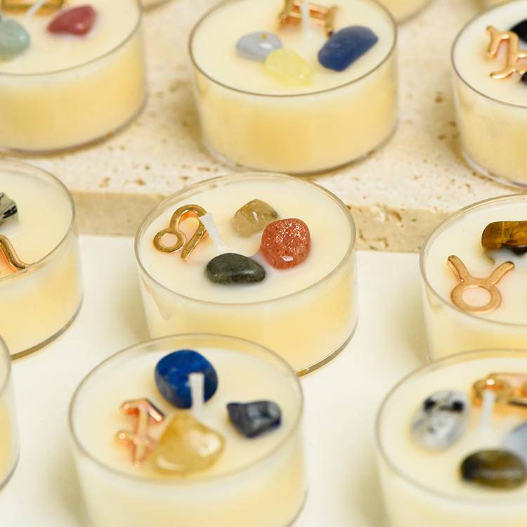 Collection grid of Zodiac gemstone tea-light candles with gold zodiac charms and mixed crystals set in creamy wax.