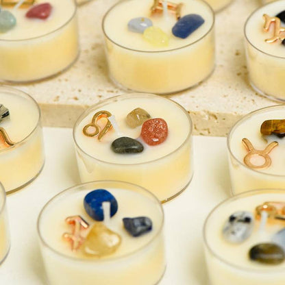 Collection grid of Zodiac gemstone tea-light candles with gold zodiac charms and mixed crystals set in creamy wax.